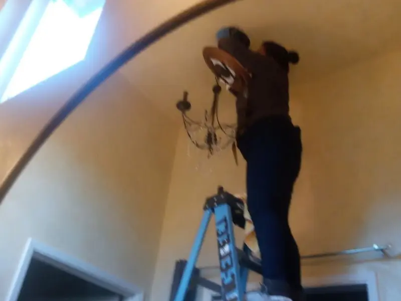 Electrician installing a chandelier in a Greenville residence